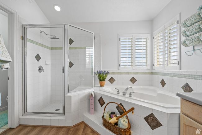 Bathroom with wood finished floors, a bath, a stall shower, and vanity | Image 39