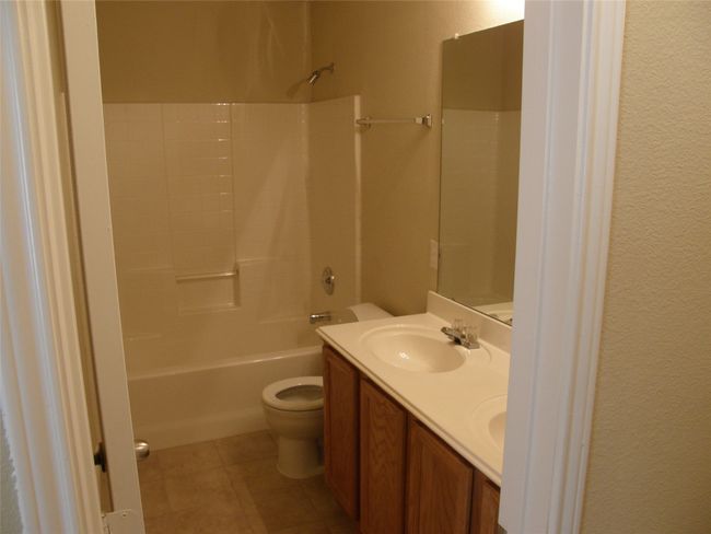 Bathroom featuring double vanity, shower combination, tile patterned floors, and a textured wall | Image 13