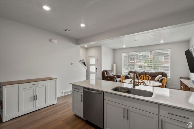 Kitchen featuring open floor plan, stainless steel dishwasher, dark wood-type flooring, recessed lighting, and light stone counters | Image 8