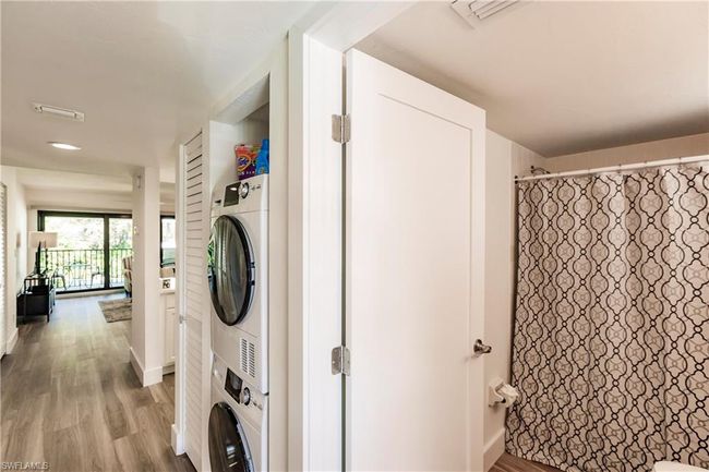 Clothes washing area with wood finished floors, stacked washer and clothes dryer, and laundry area | Image 22