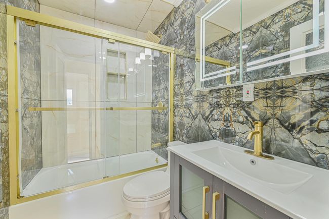Full bathroom featuring vanity, tile walls, shower / bath combination with glass door, and toilet | Image 25