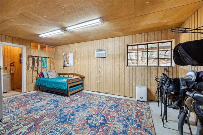 A spacious and convenient living area multitasks as a coveted tack room and features a half bath. This versatile space keeps all the essential riding equipment like saddles and bridles organized and within reach. | Image 44