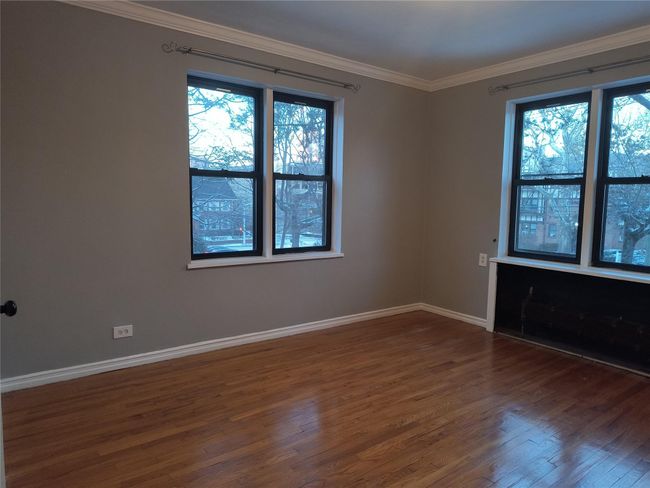 Unfurnished room featuring a healthy amount of sunlight, baseboards, crown molding, and dark wood-type flooring | Image 32