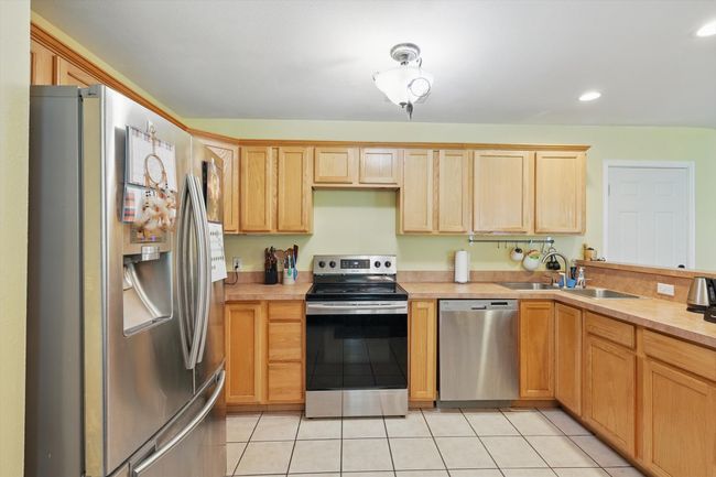 Kitchen with light countertops, light tile patterned flooring, light brown cabinetry, and appliances with stainless steel finishes | Image 12