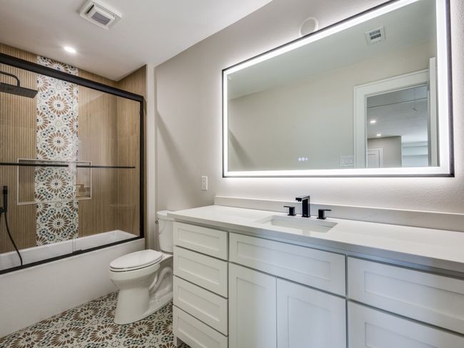 Upstairs bathroom with built in cabinets, lighted mirror with dimmer and anti-fog button, shower combo with glass door, and custom tiles-surrouund and patterned tile floors | Image 37