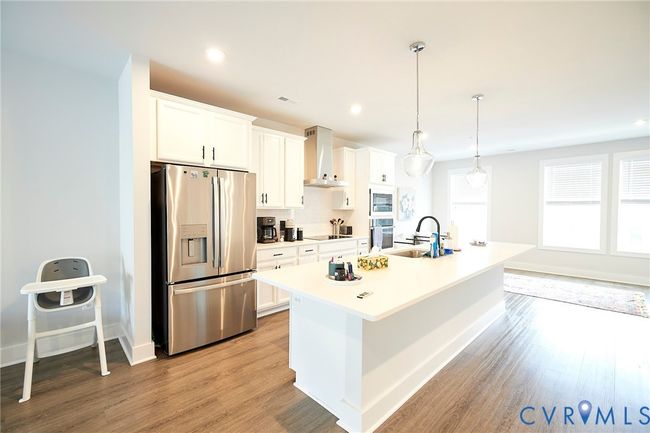Kitchen featuring stainless steel appliances, an island with sink, light wood-style floors, light countertops, and recessed lighting | Image 38