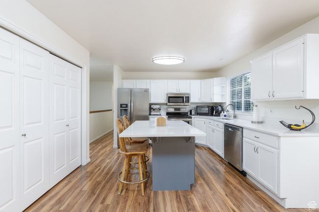 Kitchen featuring stainless steel appliances, a breakfast bar, and white cabinetry | Image 4