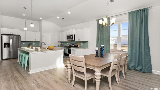 Dining space with a chandelier, light wood-style floors, recessed lighting, and high vaulted ceiling | Image 9