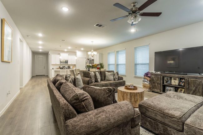 Living room featuring baseboards, a chandelier, light wood-type flooring, recessed lighting, and a ceiling fan | Image 4