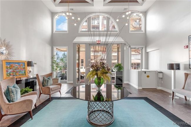 Sitting room with a high ceiling, tile patterned flooring, baseboards, and an inviting chandelier | Image 5
