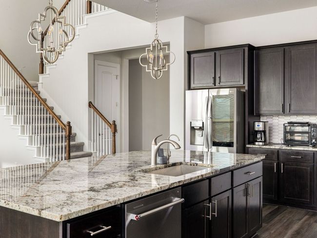 Kitchen with dark wood-style flooring, stainless steel appliances, a chandelier, decorative backsplash, and a sink | Image 7