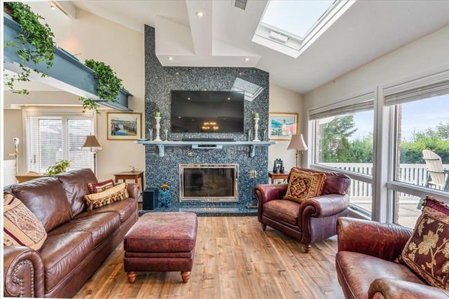 Living room featuring vaulted ceiling, a skylight, wood finished floors, and a premium fireplace | Image 12