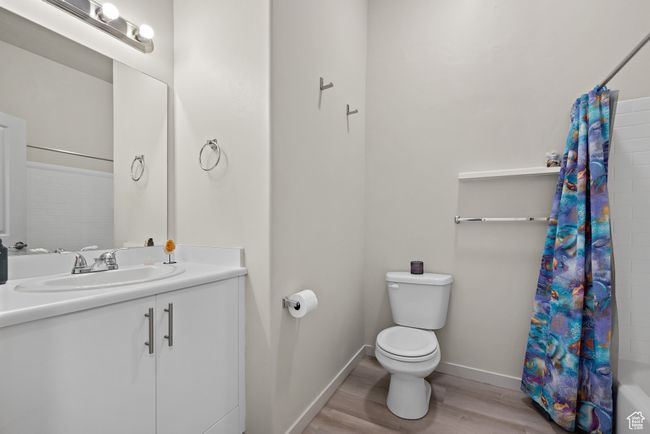 Bathroom with wood finished floors, vanity, and shower / bathtub combination with curtain | Image 13