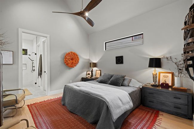 Bedroom with light wood-style floors, high vaulted ceiling, ensuite bathroom, and ceiling fan | Image 23