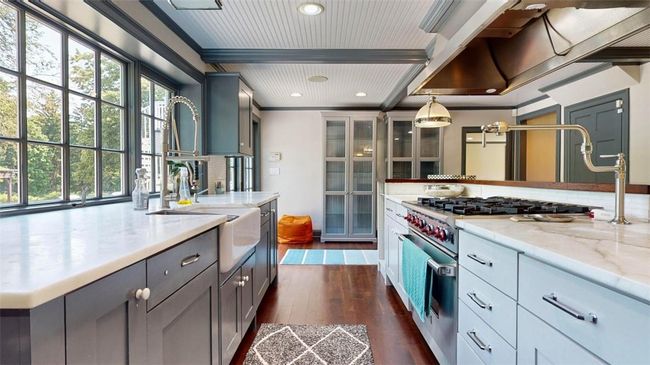 Kitchen featuring dark hardwood / wood-style flooring, gray cabinetry, light stone countertops, designer stove, and pendant lighting | Image 10
