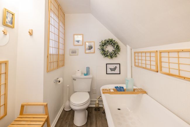 Bathroom featuring wood finished floors, a freestanding bath, toilet, and vaulted ceiling | Image 13