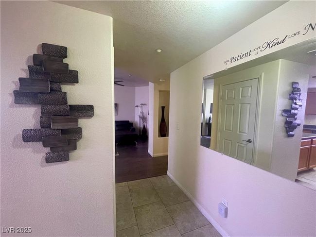 Corridor featuring tile patterned flooring, a textured ceiling, and baseboards | Image 15