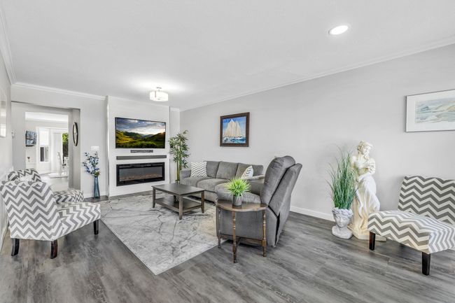 Living room with ornamental molding, baseboards, a glass covered fireplace, and wood finished floors | Image 7