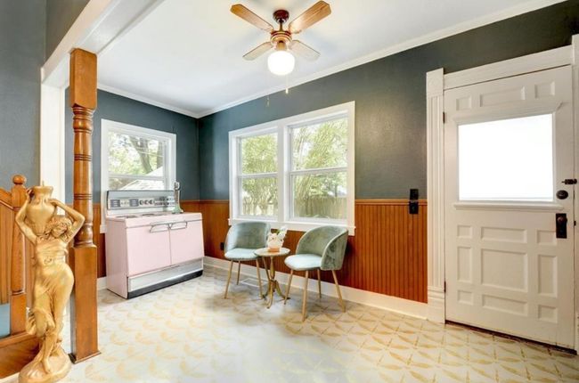 Side kithcen area featuring tile patterned floors, wainscoting, ceiling fan, wooden walls, and ornamental molding | Image 16