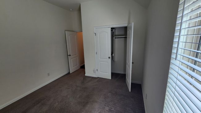 Unfurnished bedroom featuring dark colored carpet and baseboards | Image 17