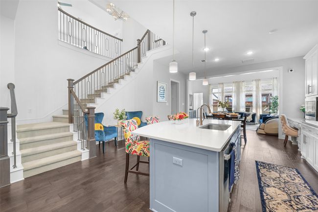 Kitchen featuring dark wood-style floors, a sink, a center island with sink, light countertops, and a breakfast bar | Image 11