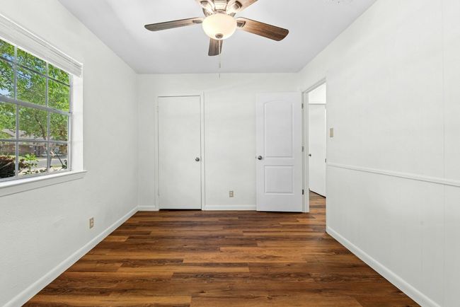 Unfurnished bedroom with dark wood-style floors and ceiling fan | Image 11
