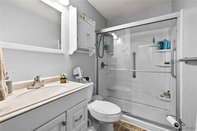Bathroom with toilet, vanity, a textured ceiling, and a stall shower | Image 13