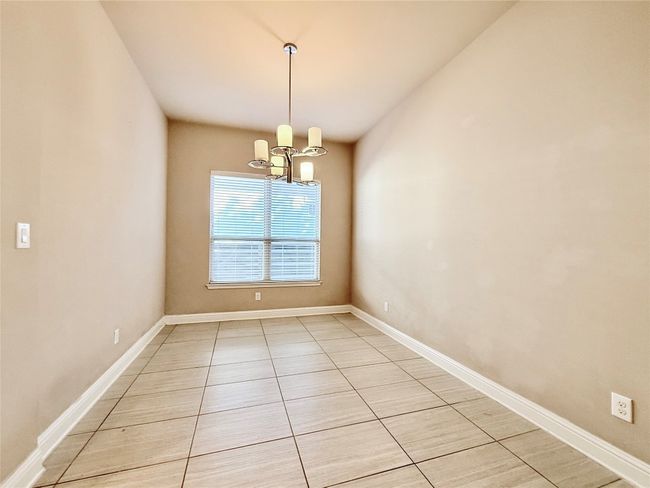 Empty room with a chandelier and light tile patterned flooring | Image 21