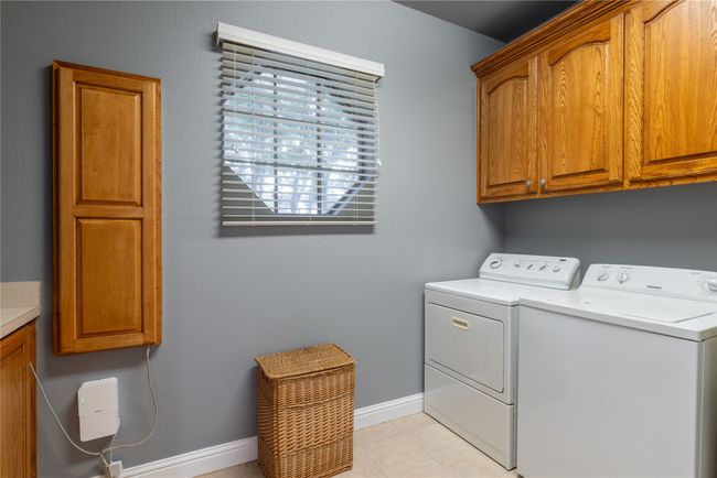 Laundry area featuring cabinet space, independent washer and dryer, sink and tile flooring | Image 27