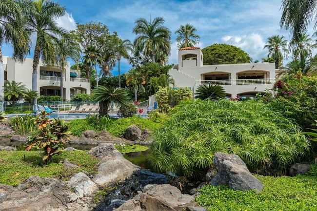 Flowing through the center courtyard from the pool area is a graceful stream with waterfalls that | Image 39