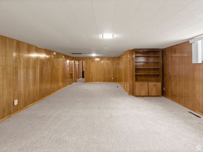 Finished below grade area with pristine paneling, light colored carpet, and built in features | Image 23
