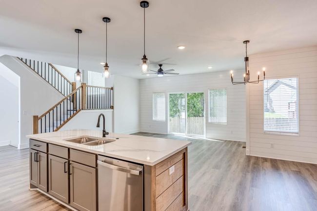 Kitchen with stainless steel dishwasher, a sink, light wood finished floors, open floor plan, and hanging light fixtures | Image 10