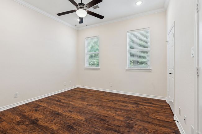 Empty room with ceiling fan, crown molding, dark wood-style flooring, and recessed lighting | Image 18