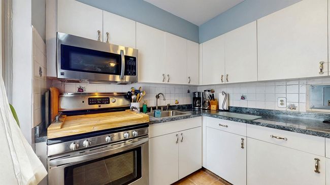 Kitchen featuring appliances with stainless steel finishes, backsplash, and white cabinets | Image 13