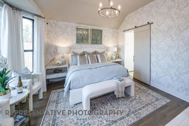 Bedroom featuring wallpapered walls, vaulted ceiling, a barn door, wood finished floors, and a chandelier | Image 16