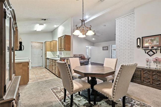 Dining space featuring lofted ceiling, light colored carpet, a chandelier, and a textured ceiling | Image 19