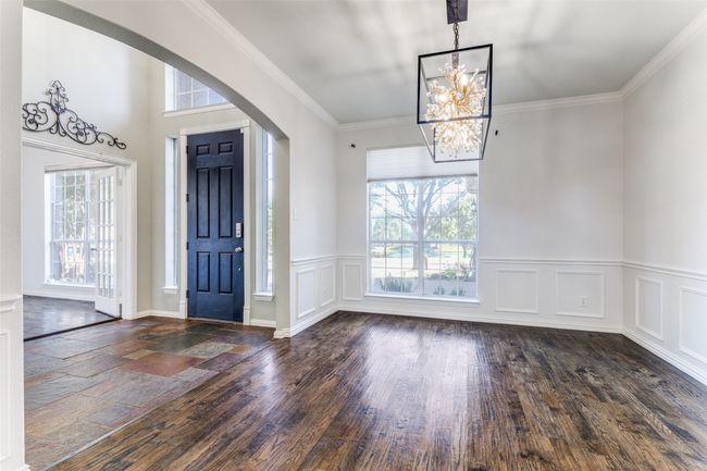 Entrance foyer featuring arched walkways, a chandelier, wood finished floors, wainscoting, and crown molding | Image 6