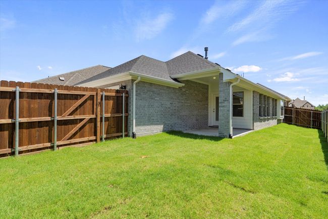 Rear view of house with a shingled roof, brick siding, a gate, and a patio area | Image 22
