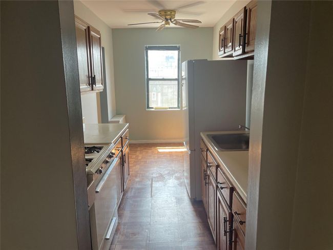 Kitchen with range with gas cooktop, a sink, light floors, a ceiling fan, and light countertops | Image 6