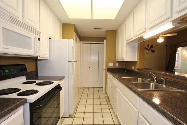 Kitchen with white appliances, a sink, white cabinetry, and light tile patterned floors | Image 6