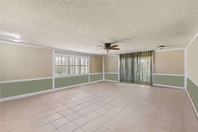 Spare room featuring baseboards, ornamental molding, light tile patterned floors, a textured ceiling, and ceiling fan | Image 32