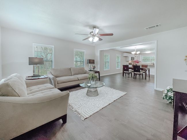 Living room with a chandelier, wood finished floors, and ceiling fan | Image 6
