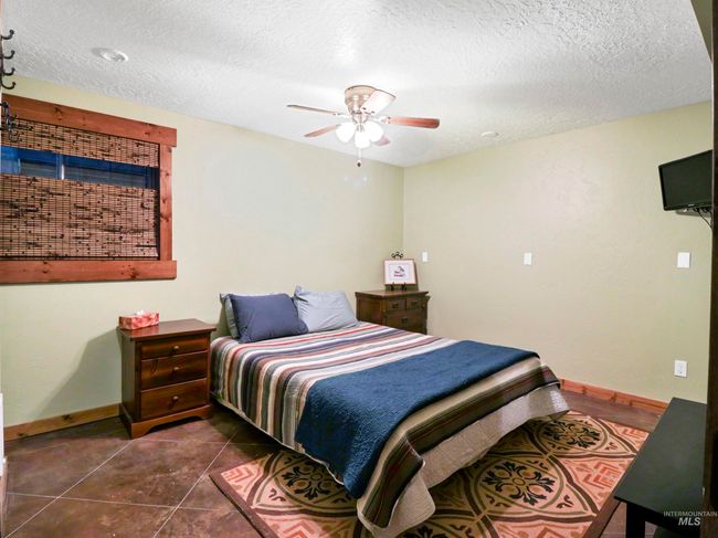 Bedroom with a textured ceiling, dark tile patterned flooring, and ceiling fan | Image 34