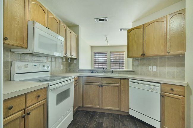 Kitchen featuring tasteful backsplash, sink, light brown cabinets, and white appliances | Image 11
