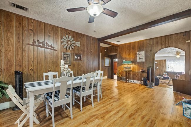 Dining area with wood finished floors, visible vents, arched walkways, and ceiling fan | Image 9