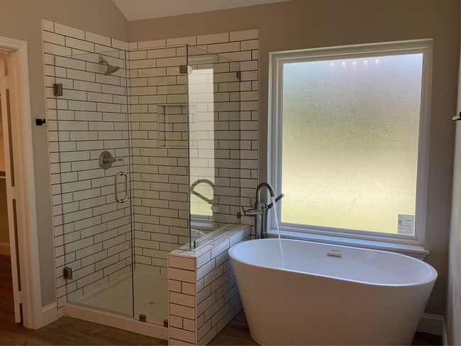 Bathroom with a stall shower, a freestanding bath, plenty of natural light, wood finished floors, and lofted ceiling | Image 20