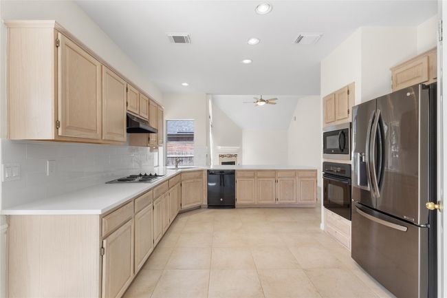 Kitchen featuring light brown cabinets, black appliances, a ceiling fan, a peninsula, and recessed lighting | Image 10