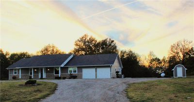 Single story home featuring a lawn, a storage unit, a garage, and covered porch | Image 2