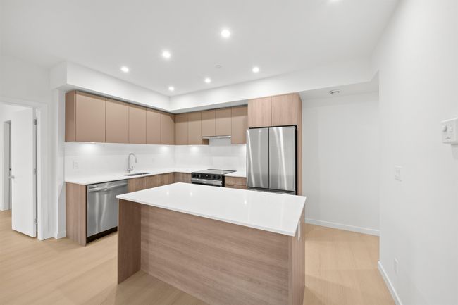 Kitchen with appliances with stainless steel finishes, modern cabinets, recessed lighting, a center island, and light countertops | Image 6