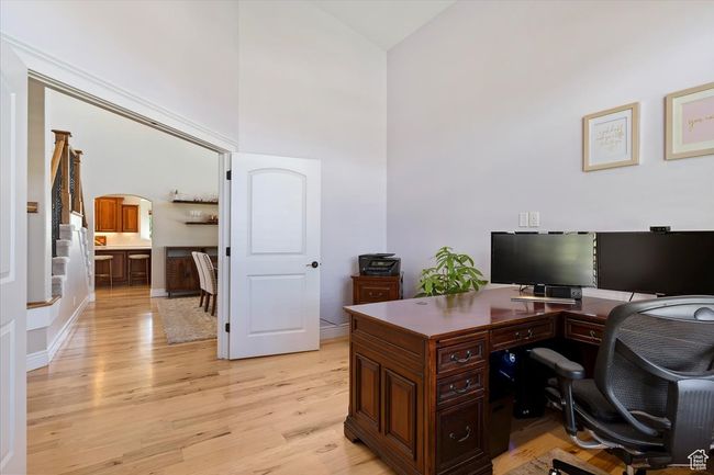 Office area featuring arched walkways, light wood finished floors, and high vaulted ceiling | Image 26